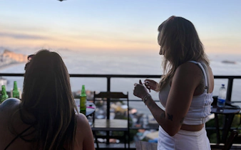Women enjoying drinks with ocean view from Vidigal, Rio de Janeiro.