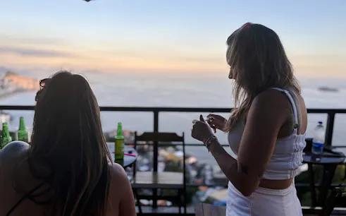 Women enjoying drinks with ocean view from Vidigal, Rio de Janeiro.