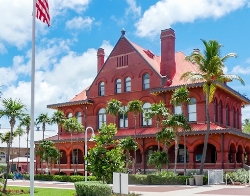 Historic red brick building at St. Augustine History Museum, surrounded by palm trees.