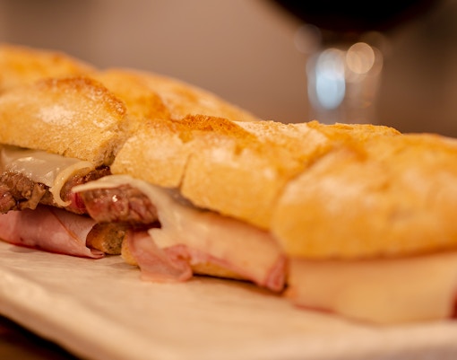 Prego no Pao sandwich with steak and cheese on a plate.