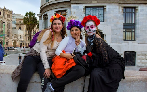 Tourists in traditional Day of the Dead attire at a parade in Mexico City.