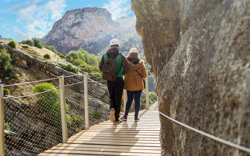 Visitors walking on Caminito del Rey path with mountain view in Spain.