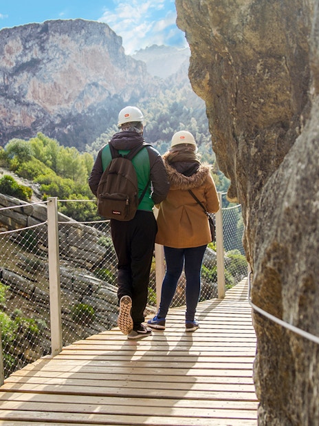 Visitors walking on Caminito del Rey path with mountain view in Spain.