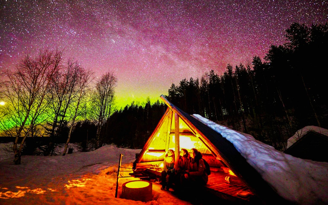 Chasing Northern Lights in Rovaniemi with traditional barbecue under starry sky.