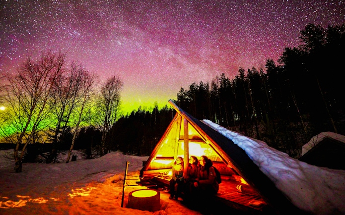 Chasing Northern Lights in Rovaniemi with traditional barbecue under starry sky.