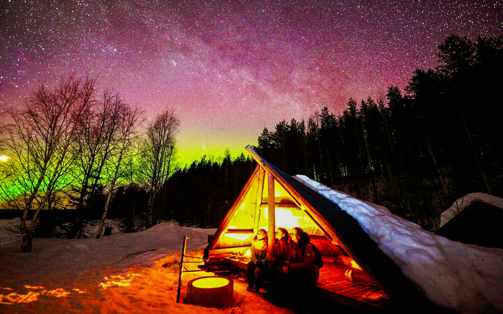 Chasing Northern Lights in Rovaniemi with traditional barbecue under starry sky.