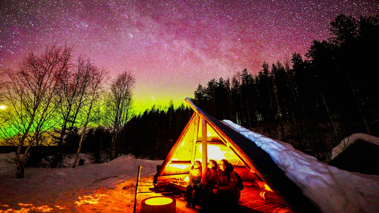 Chasing Northern Lights in Rovaniemi with traditional barbecue under starry sky.