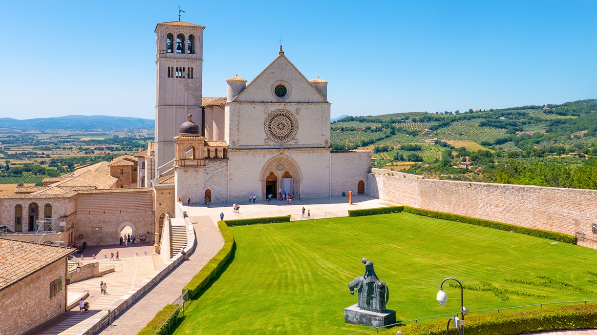 Basilica of Saint Francis of Assisi exterior with intricate stone facade and bell tower in Assisi, Italy.