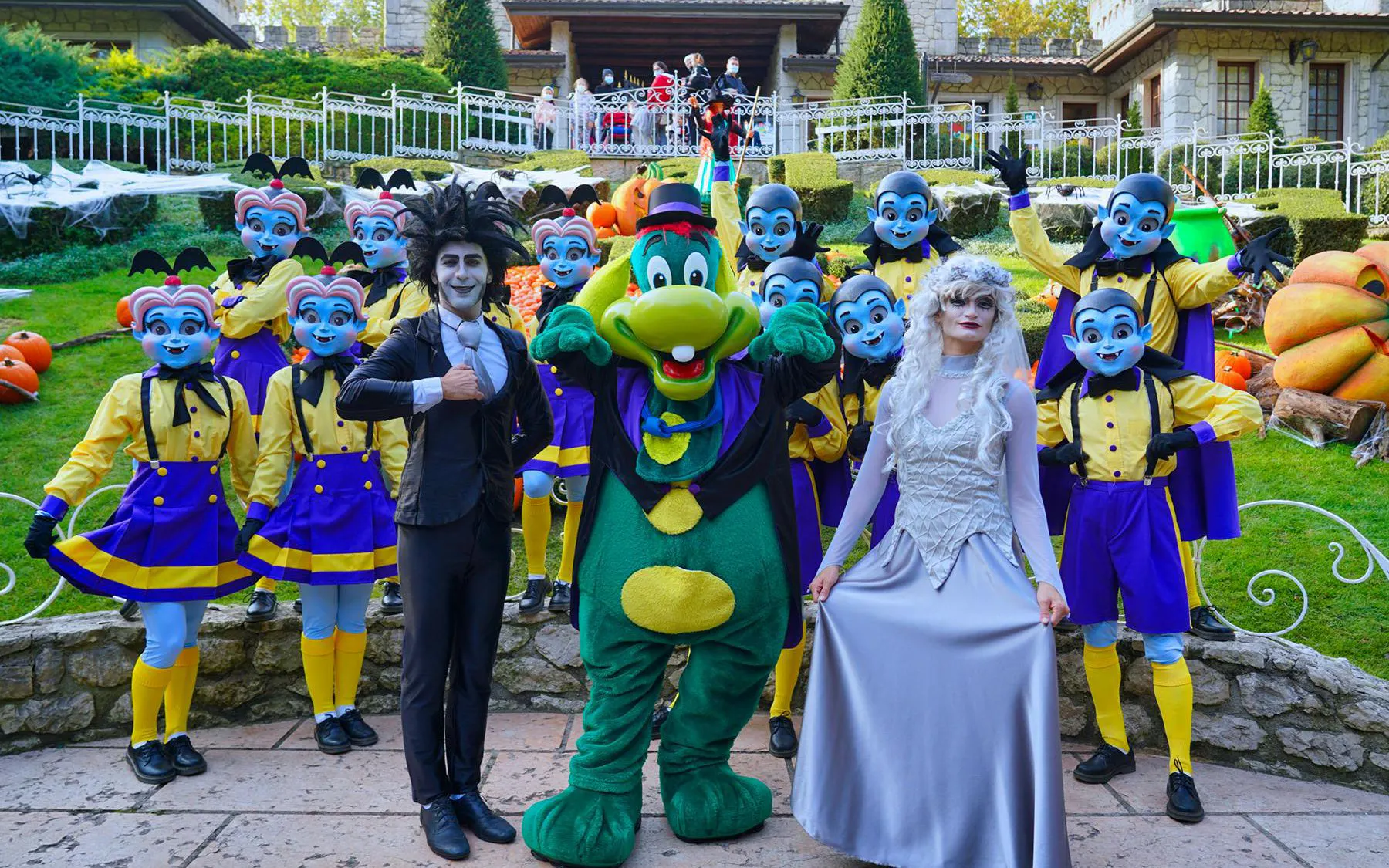 Gardaland Halloween performers in colorful costumes with pumpkins in the background.
