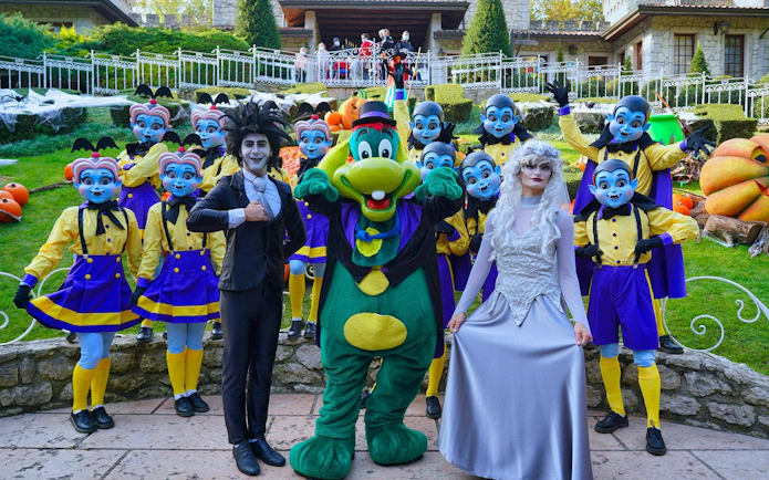 Gardaland Halloween performers in colorful costumes with pumpkins in the background.