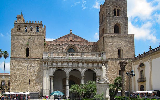 Monreale Cathedral facade with arches and towers, Sicily, on a sunny day.