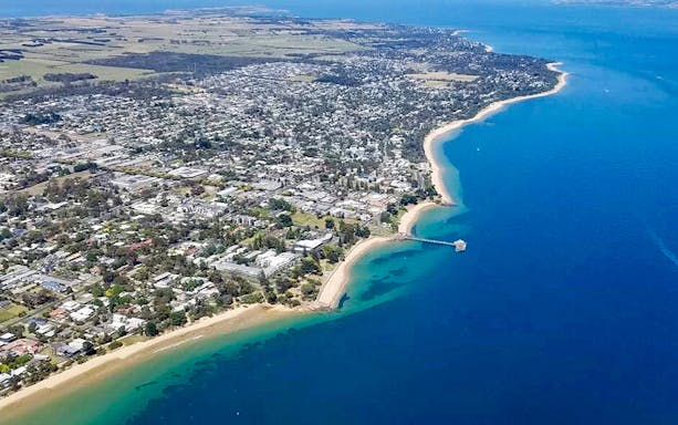 Aerial view of Phillip Island coastline and town during scenic helicopter flight.