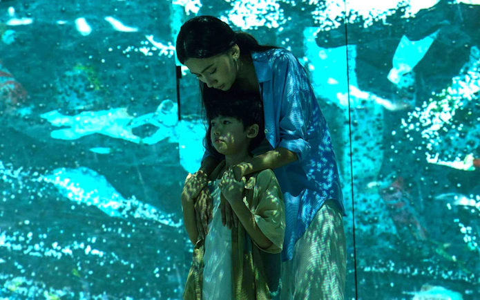 Child and adult in front of an ocean-themed digital display, symbolizing a better future.