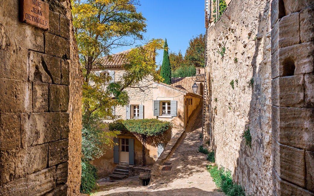 Stone alleyway in Sault, France, with rustic buildings and greenery.