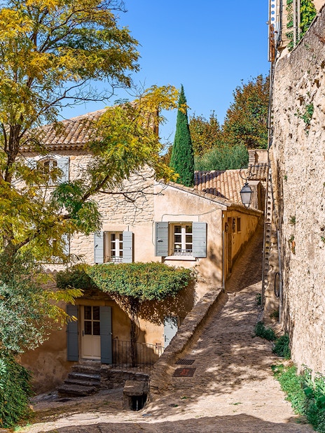 Stone alleyway in Sault, France, with rustic buildings and greenery.