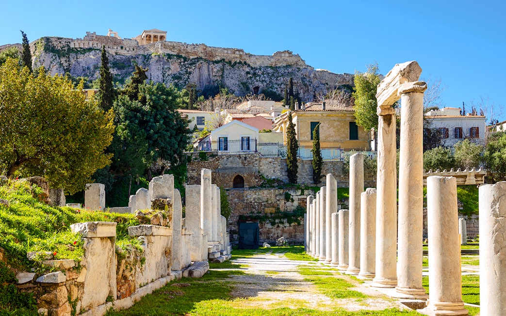 Ancient agora ruins with stone pillars in Athens, Greece, under the Acropolis.
