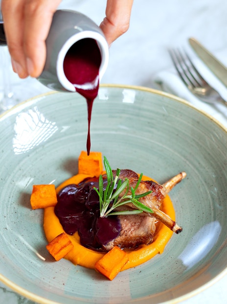 Lamb dish with sauce being poured, served on Bustronome London tour.