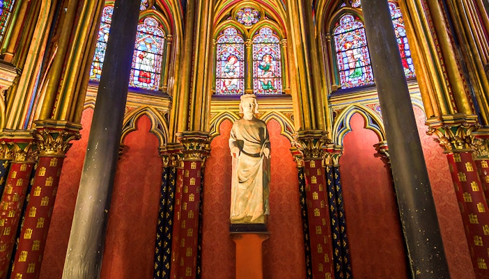 Mall altar surrounded by statues of saints in a historic church setting.