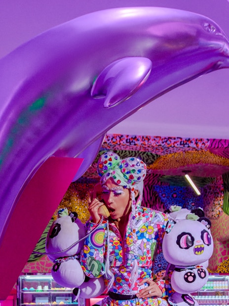 Person in colorful outfit at phone booth, Enchanted Carnival, Halloween Experience, House of Hype.