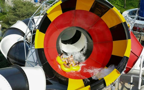 Water slide at Hurricane Harbor Chicago with people on a yellow raft.