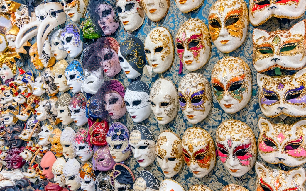 Venetian carnival masks displayed on a wall in Venice, Italy.