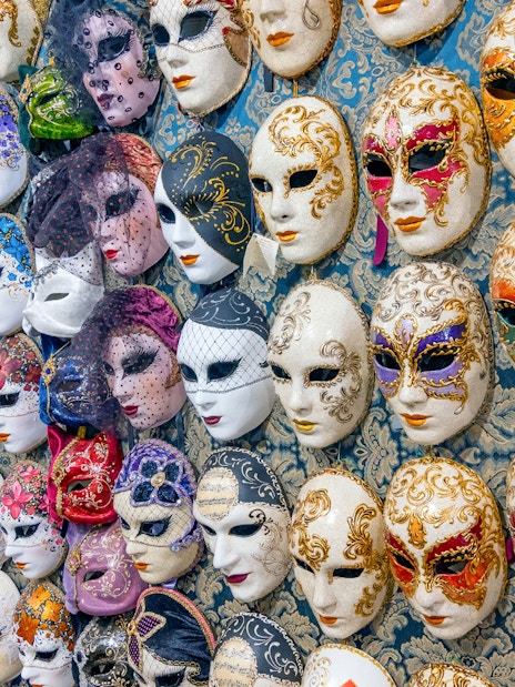 Venetian carnival masks displayed on a wall in Venice, Italy.
