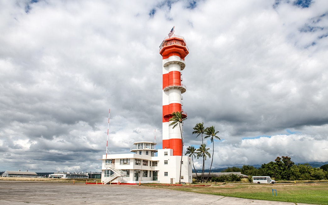 Pearl Harbor airport control tower with cloudy sky backdrop.