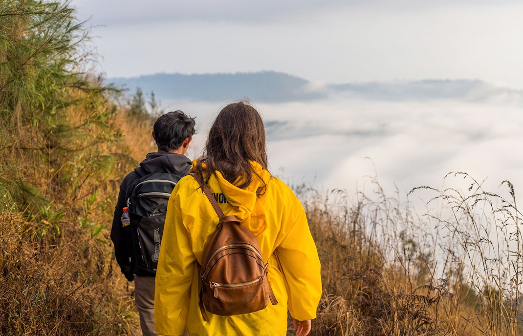 Hikers walking along a trail with misty views at Mount Batur.