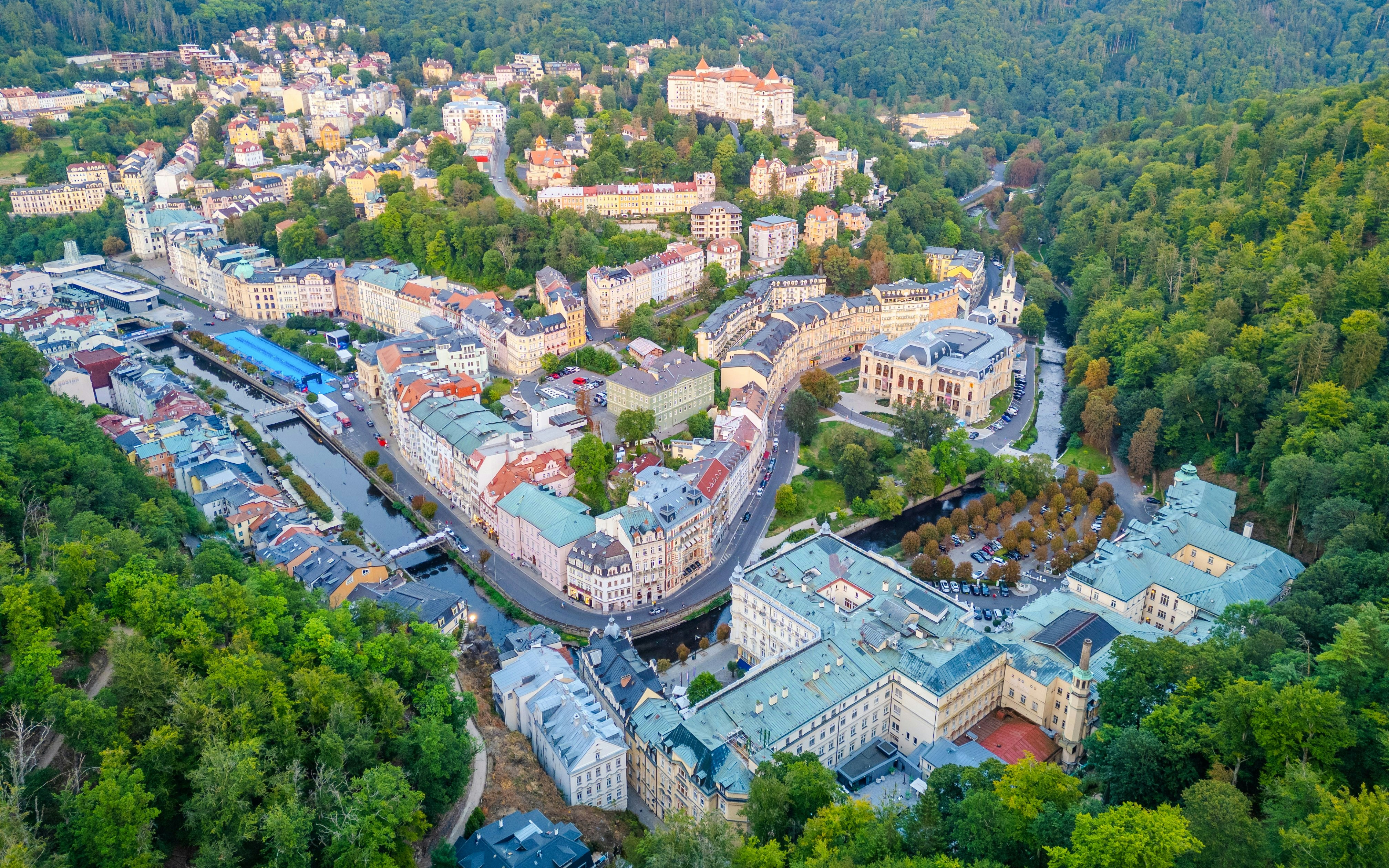 Sunset panorama of Karlovy Vary with historic hotels and lush greenery.