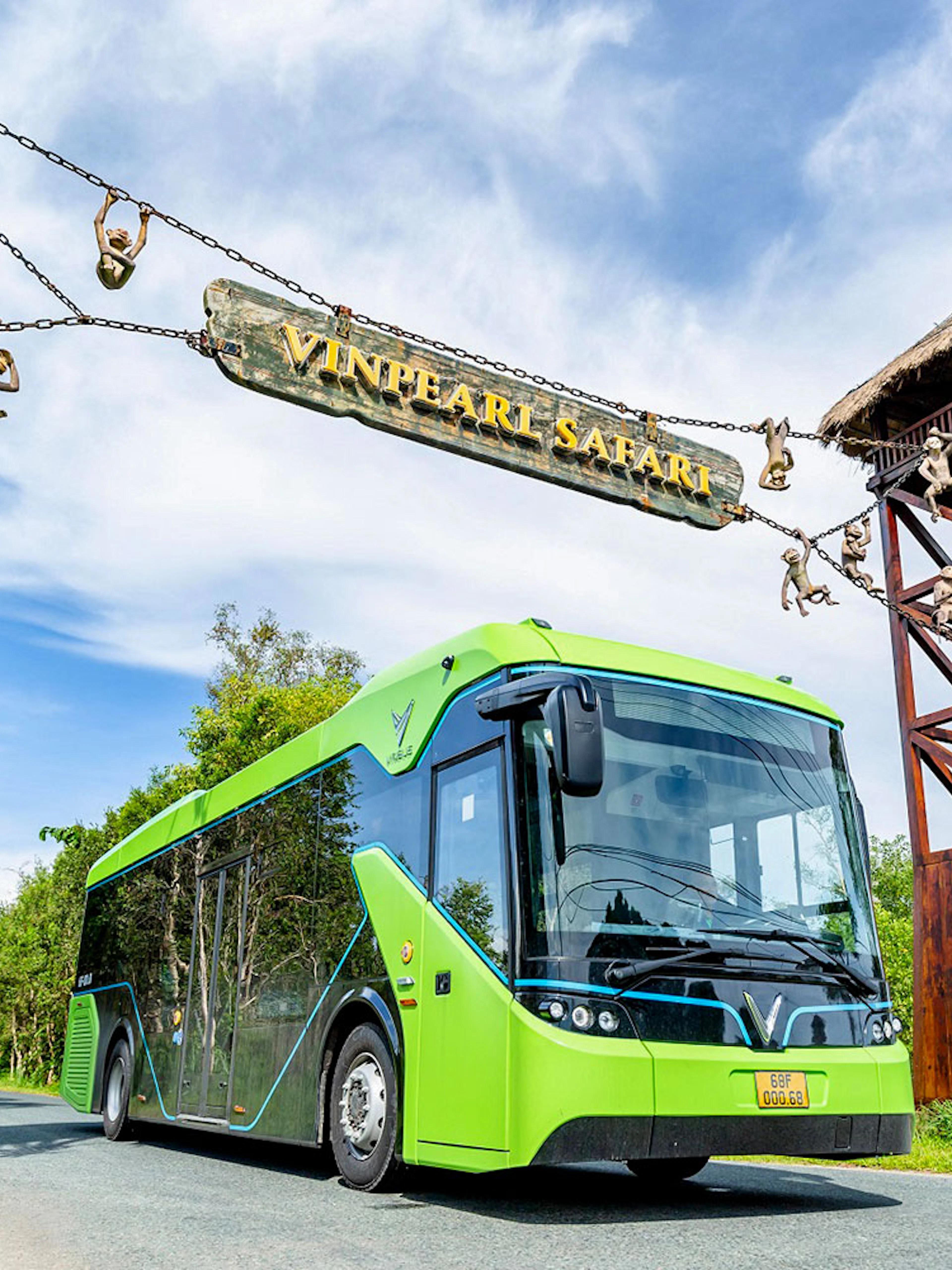 Bus entering Vinpearl Safari under entrance sign with monkey sculptures.