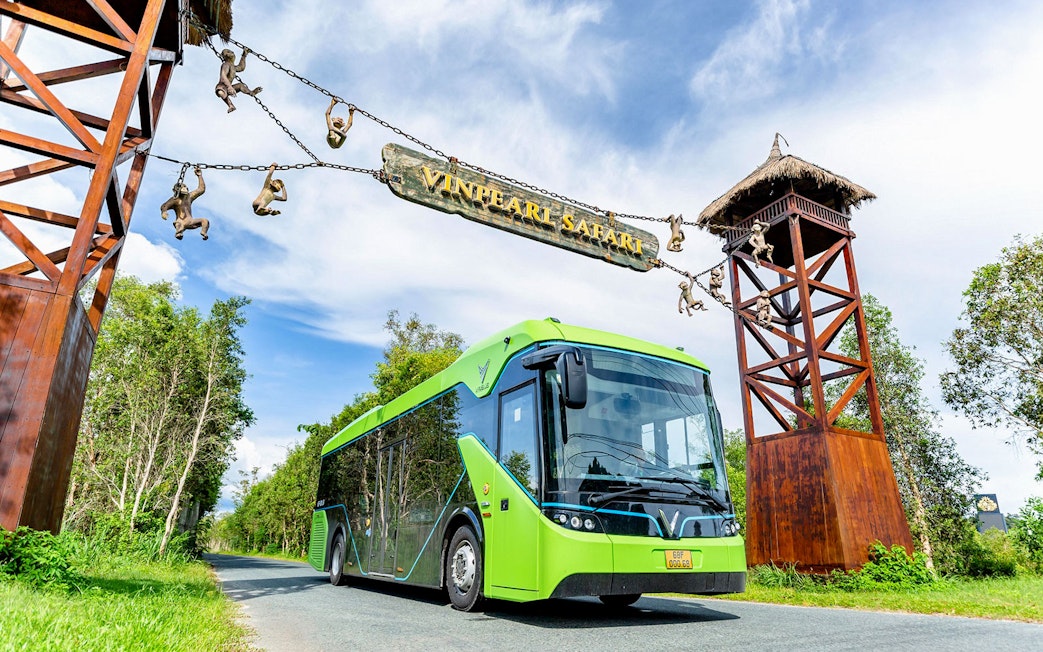 Bus entering Vinpearl Safari under entrance sign with monkey sculptures.