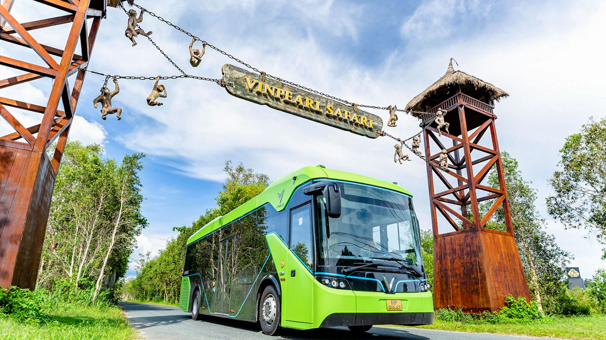 Bus entering Vinpearl Safari under entrance sign with monkey sculptures.