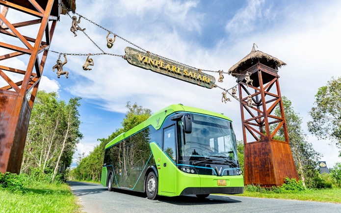 Bus entering Vinpearl Safari under entrance sign with monkey sculptures.
