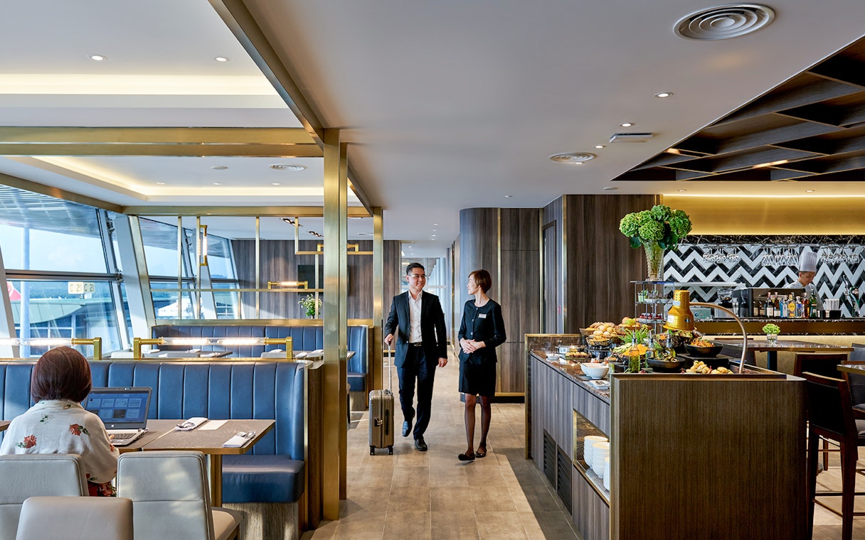 Plaza Premium Lounge at Langkawi Airport with guests and buffet area.