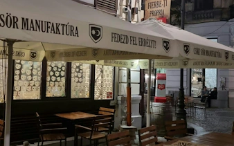 Outdoor seating area of a Bucharest café with Hungarian signage, part of Jewish Bucharest exploration game.