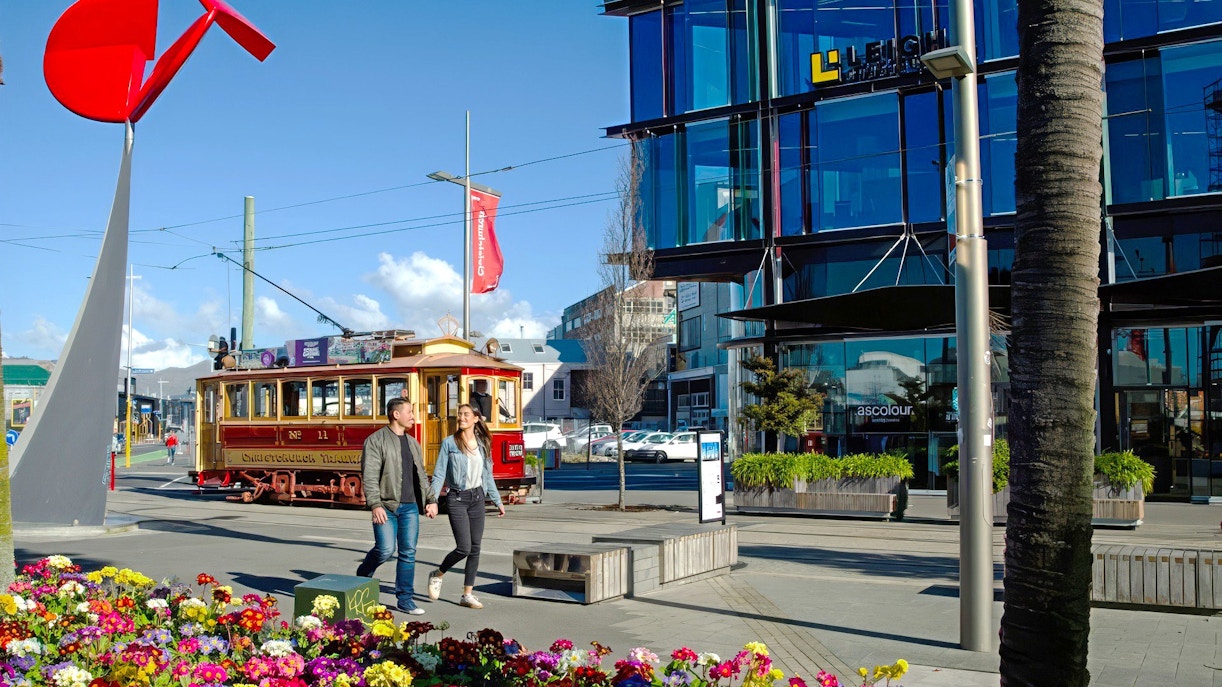 Couple walking near tram in Christchurch city center.