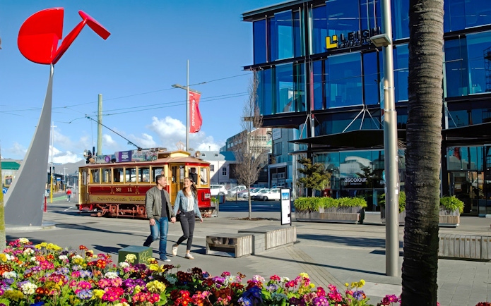 Couple walking near tram in Christchurch city center.