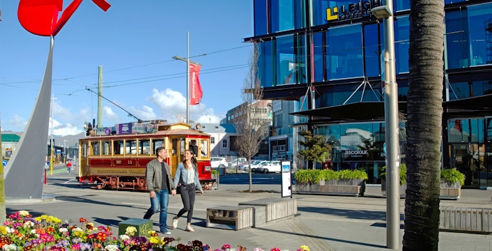Couple walking near tram in Christchurch city center.