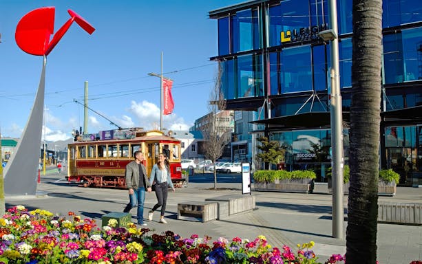 Couple walking near tram in Christchurch city center.