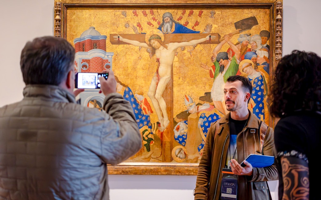 Guide with tourists viewing a painting inside the Louvre Museum, France.