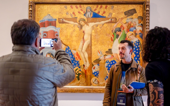 Guide with tourists viewing a painting inside the Louvre Museum, France.