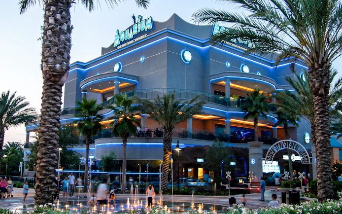 Downtown Aquarium Houston exterior with palm trees and evening lights.