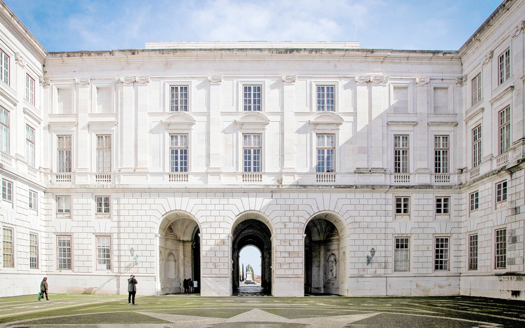 Courtyard of National Palace of Ajuda, Lisbon with arched entrance and visitors.