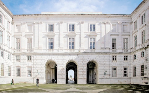 Courtyard of National Palace of Ajuda, Lisbon with arched entrance and visitors.