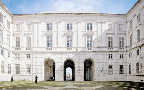 Courtyard of National Palace of Ajuda, Lisbon with arched entrance and visitors.