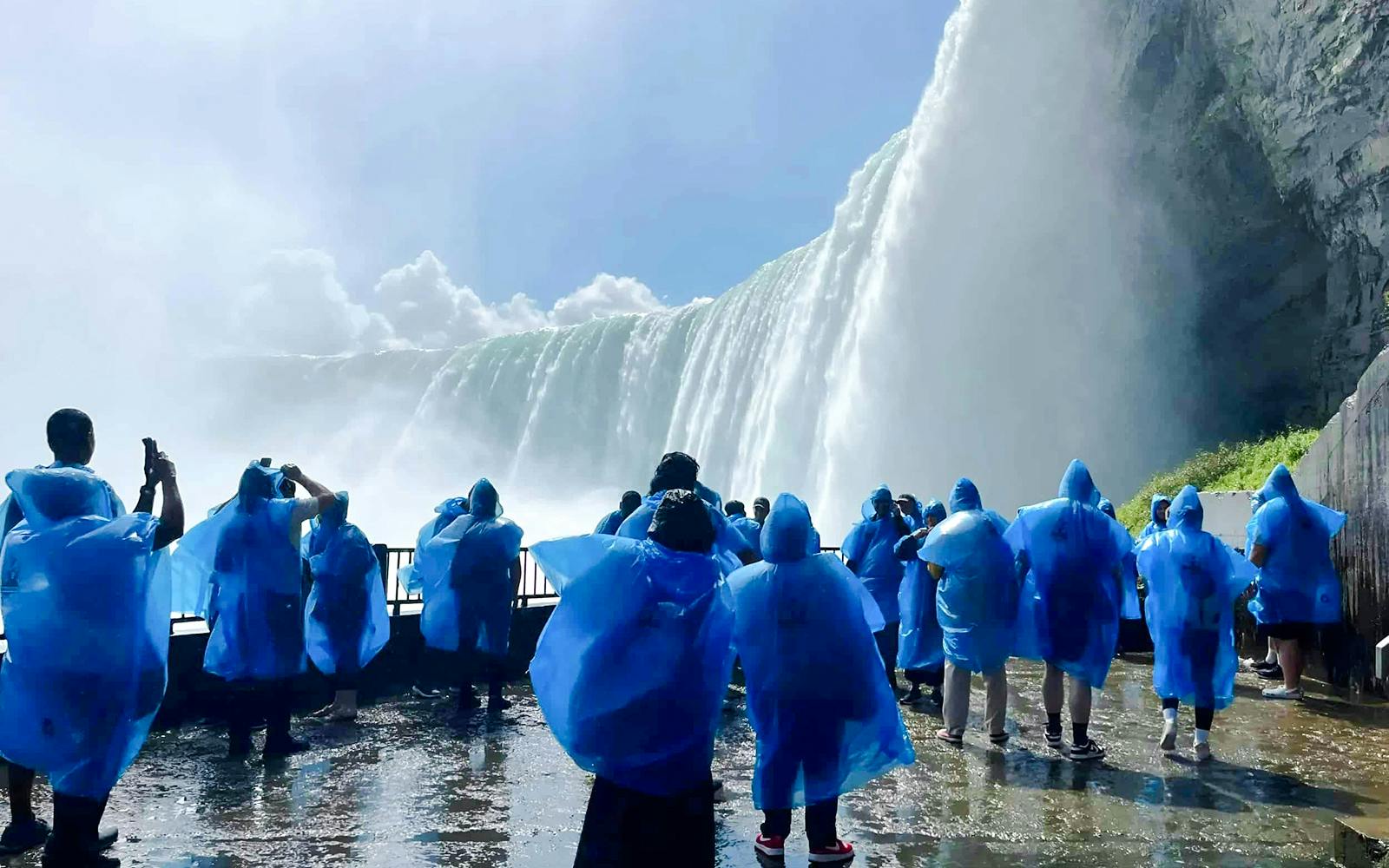 Visitors in blue ponchos viewing Niagara Falls from a close vantage point in Canada.