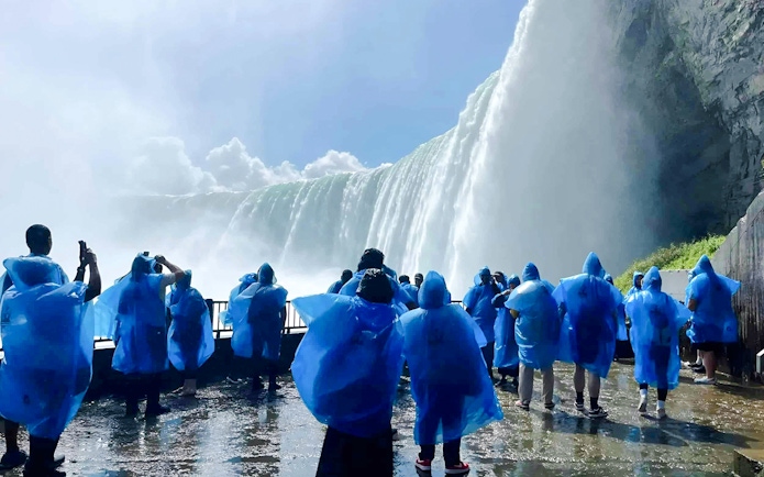 Visitors in blue ponchos viewing Niagara Falls from a close vantage point in Canada.