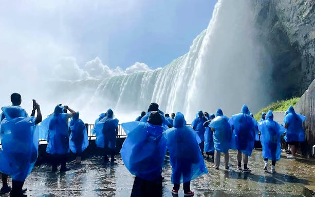Visitors in blue ponchos viewing Niagara Falls from a close vantage point in Canada.