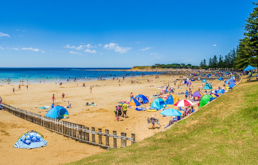 Torquay Beach along Great Ocean Road with surfers catching waves in the background.