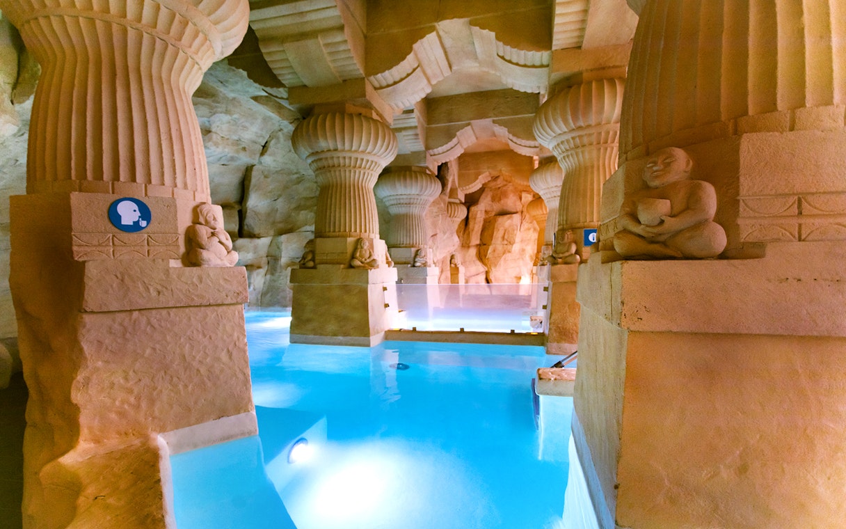 Thermal spa area with stone columns and blue water at Caldea, Andorra.